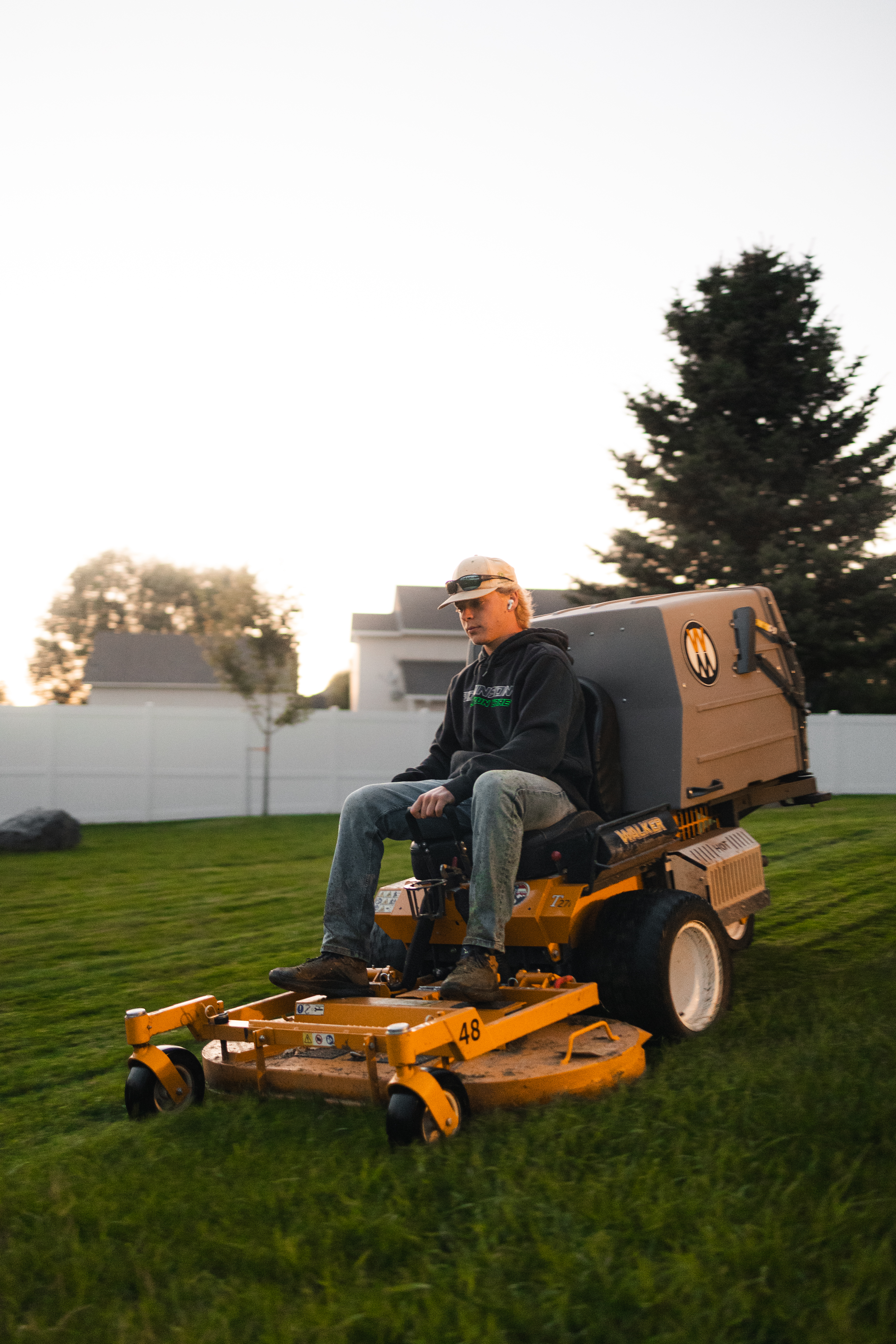 Robinson Lawn Care tech mowing an emerald green lawn with the sunset in the background