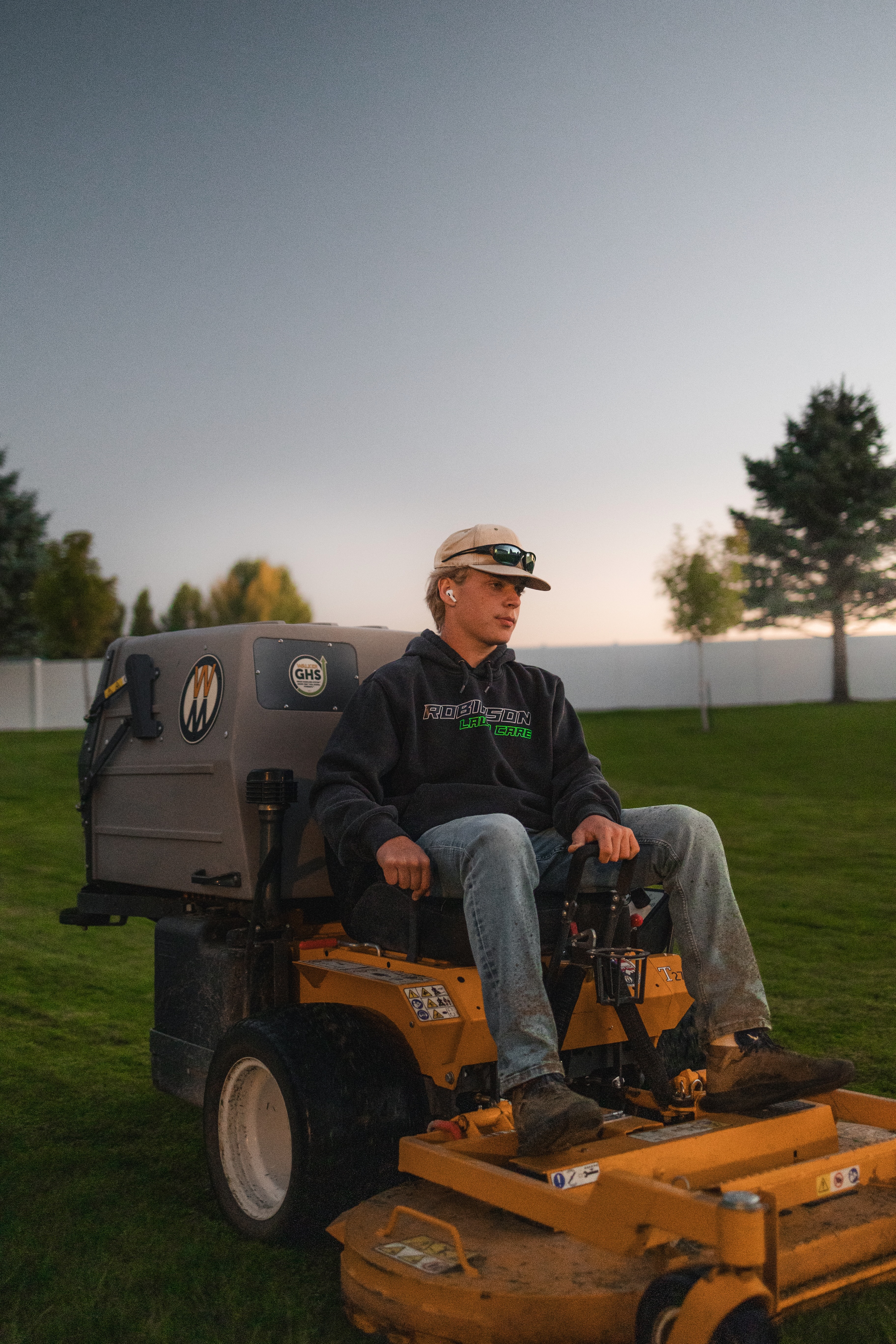 Robinson Lawn Care tech mowing an emerald green lawn with the sunset in the background